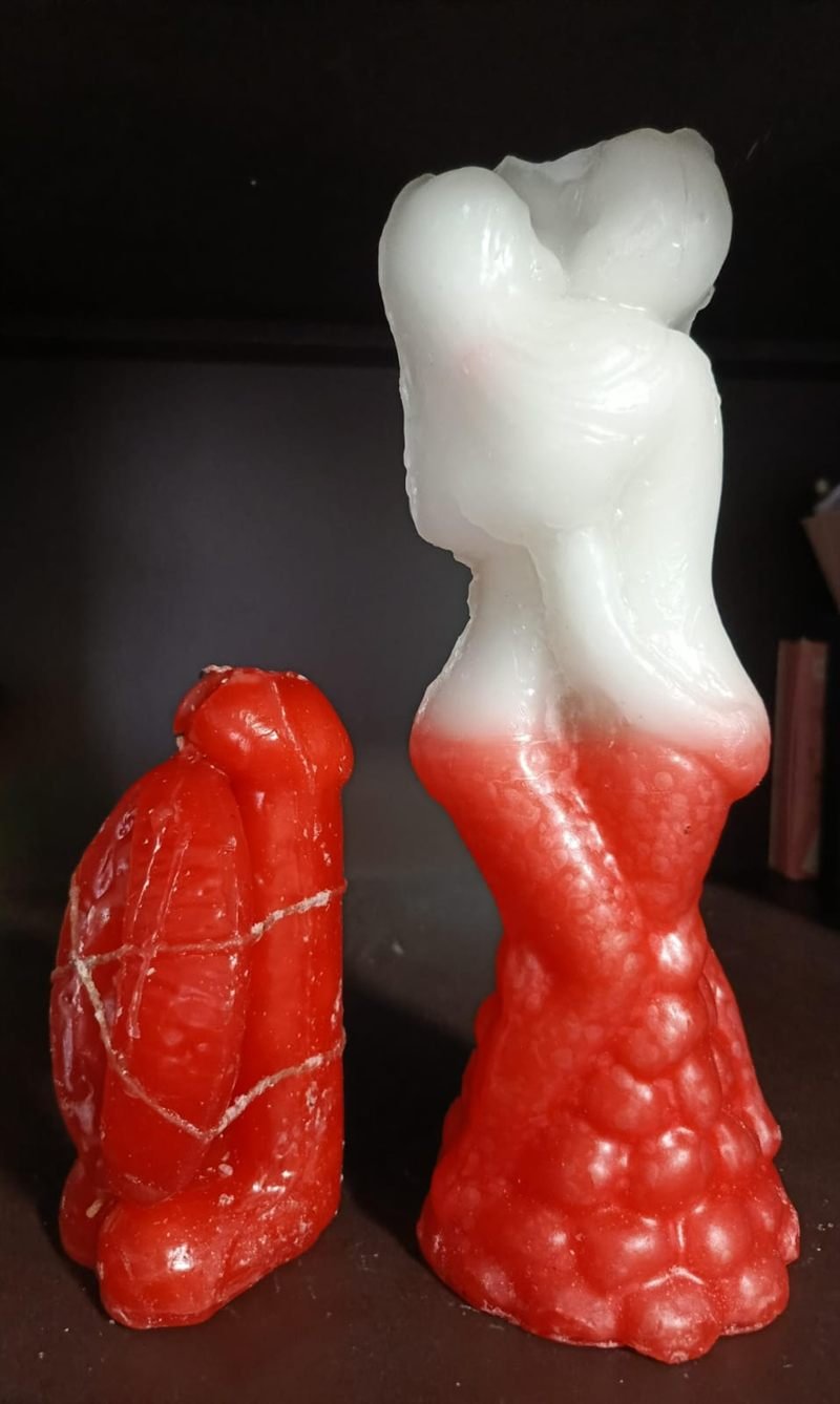 Velas rojas y blancas con forma de pareja abrazada, atadas con cordón