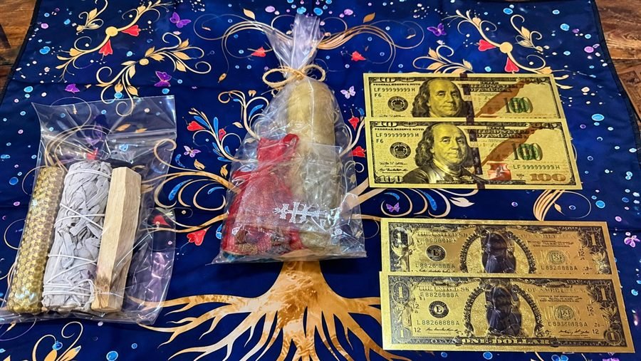 Kit espiritual con salvia, palo santo, vela dorada, bolsita de hierbas y billetes dorados sobre un paño azul con el árbol de la vida